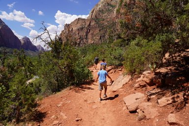Eine Familie wandert auf einem schmalen Pfad durch die beeindruckende Landschaft des Zion-Nationalparks.