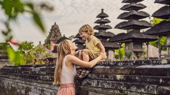 Mutter mit Kind beim Besuch eines balinesischen Tempels – Bali Familienreise