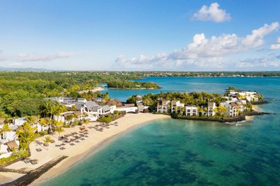 Ein atemberaubender Blick auf das luxuriöse Resort am Strand, umgeben von üppigem Grün und klarem, blauem Wasser.