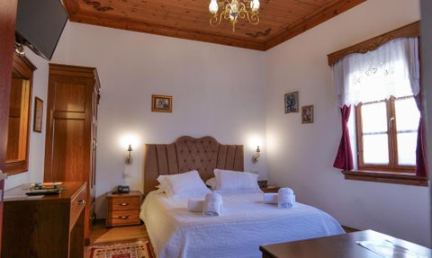 Ein gemütliches Hotelzimmer mit einem großen Bett, Holzdecke und warmen Farben, ideal für einen entspannten Aufenthalt.