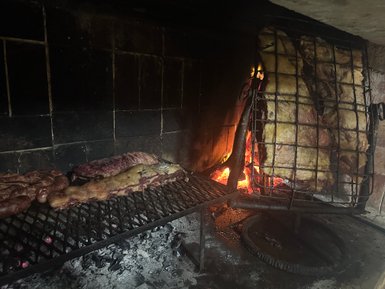 Ein Grill mit verschiedenen Fleischstücken, die über glühenden Kohlen zubereitet werden, strahlt ein einladendes Aroma aus.