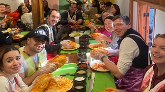 Eine Gruppe von Menschen sitzt an einem Tisch und hält stolz ihre selbstgemachten Kimchi-Teile in den Händen.