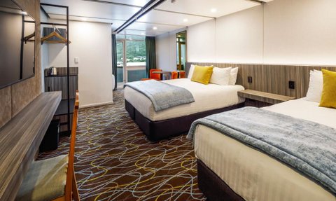 Zwei komfortable Betten mit hellen Kissen und einer warmen Decke in einem modernen Hotelzimmer.