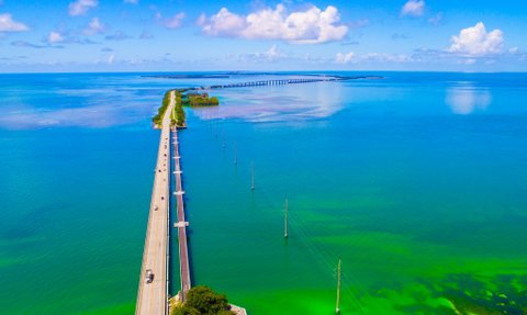 Eine malerische Aussicht auf die lange Brücke, die über das türkisfarbene Wasser von Florida führt, umgeben von üppigem Grün.