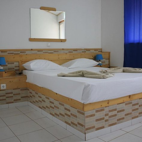 Ein modernes Schlafzimmer mit einem großen Bett, einem Spiegel und blauen Vorhängen, das eine entspannende Atmosphäre ausstrahlt.