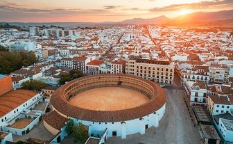 Die Arena von Ronda erhebt sich majestätisch über die Stadt, während die Sonne hinter den Bergen untergeht.
