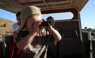 Kind beobachtet mit einem Fernglas während einer Safari – Südafrika Reise mit Kindern