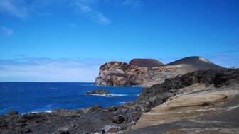 Eine beeindruckende Küstenlandschaft mit schroffen Felsen und klarem, blauem Wasser unter einem strahlend blauen Himmel.