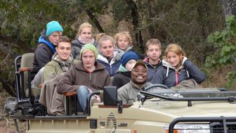 Gruppe mit erfahrenem Guide im offenen Jeep auf Safari durch die kühle Winterlandschaft Südafrikas – Südafrika Reise mit Kindern
