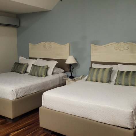 Zwei komfortable Betten mit eleganten Kopfenden und gestreiften Kissen in einem modernen Hotelzimmer.