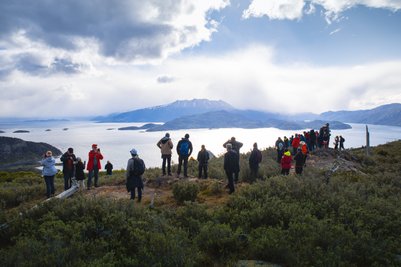 Eine Gruppe von Wanderern steht auf einem Hügel und bewundert die atemberaubende Aussicht auf die Fjorde Patagoniens.