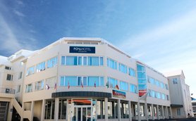 Das Fosshotel Raudara präsentiert sich mit einer modernen Fassade und großen Fenstern unter einem strahlend blauen Himmel.