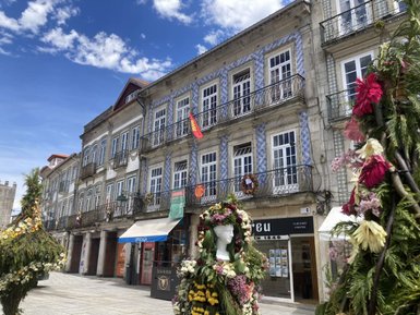 Die historische Fassade eines Gebäudes mit blauen Fliesen und Balkonen, umgeben von bunten Blumenarrangements.