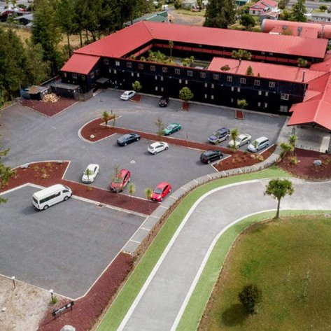 Eine Luftaufnahme des Parkhotels in Tongariro Nationalpark, umgeben von Bäumen und einem großen Parkplatz.
