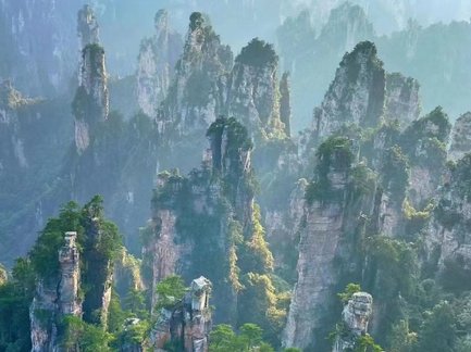 Majestätische, hoch aufragende Felsen sind von üppigem Grün umgeben, während der Nebel die Landschaft mystisch erscheinen lässt.