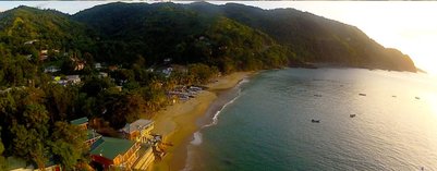Eine malerische Küstenlandschaft mit sanften Hügeln, die sich über einen ruhigen Strand erstrecken, während Boote im Wasser schaukeln.