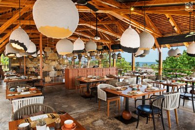 Ein stilvolles Restaurant mit Holzdecke, das von großen, hängenden Lampen in verschiedenen Formen beleuchtet wird.