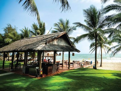 Ein einladendes Strandresort mit einem strohgedeckten Pavillon, umgeben von Palmen und Blick auf das Meer.