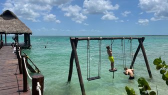 Kinder schaukeln auf einer Wasserschaukel in der Lagune von Bacalar – Mexiko Familienreise