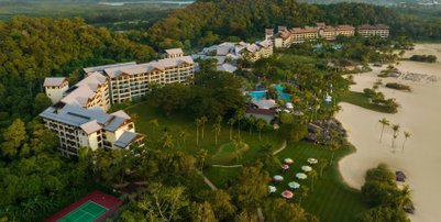 Eine weitläufige Resort-Anlage umgeben von üppigem Grün, mit mehreren Gebäuden und einem Poolbereich in der Mitte.
