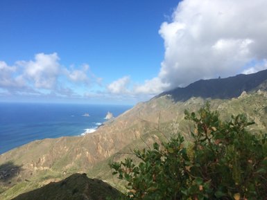Eine atemberaubende Küstenlandschaft mit steilen Bergen und dem tiefblauen Ozean unter einem klaren Himmel.