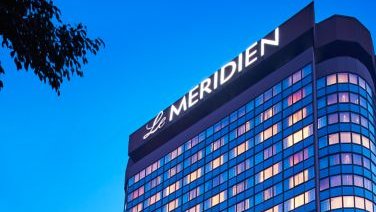Das elegante Gebäude des Le Meridien in Neu-Delhi strahlt in der Dämmerung mit leuchtenden Fenstern und modernem Design.