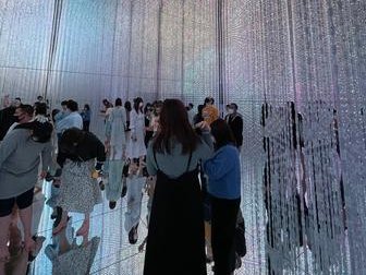 Eine Gruppe von Menschen steht in einem Raum mit schimmernden Vorhängen aus Licht, die eine traumhafte Atmosphäre schaffen.