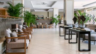 Ein eleganter Hotel-Lobby mit modernen Möbeln, großen Pflanzen und einem hellen, einladenden Ambiente.