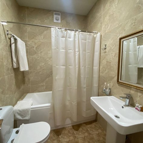 Ein modernes Badezimmer mit beige Fliesen, einer Badewanne und einem Waschbecken, das gut beleuchtet ist.