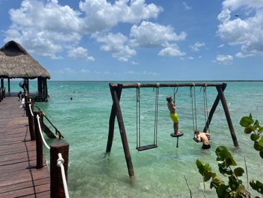 Kinder schaukeln auf einer Wasserschaukel in der Lagune von Bacalar – Mexiko Familienreise