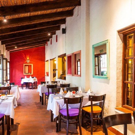 Ein einladendes Restaurant mit weißen Tischdecken und bunten Stühlen, das eine warme, gemütliche Atmosphäre ausstrahlt.