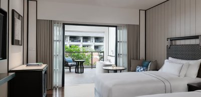 Ein elegantes Hotelzimmer mit zwei Betten, einem Balkon und Blick auf üppige Pflanzen im Freien.