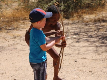 Ein Kind versucht einen Bogen zu spannen - Namibia Urlaub mit Kindern