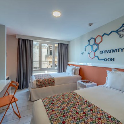 Zwei Einzelbetten mit bunten Bettüberwürfen in einem modernen Hotelzimmer, das Kreativität und Stil ausstrahlt.