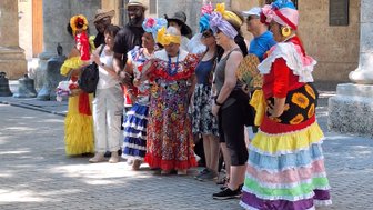 Eine Gruppe von Menschen in bunten traditionellen Kleidern posiert fröhlich unter einer Säulenarkade.