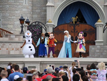 Eine Gruppe von Disney-Charakteren, darunter Elsa und Mickey Mouse, steht auf einer Bühne im Magic Kingdom.