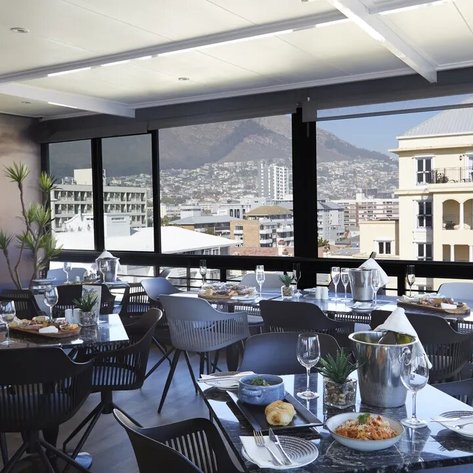 Ein eleganter Restaurantbereich mit Blick auf die Stadt und den Berg, gedeckt mit stilvollen Tischen und köstlichen Speisen.