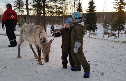 Europareisen für Familien - Finnland Familienurlaub - Finnland Winter for family - zwei Kinder streicheln Rentier
