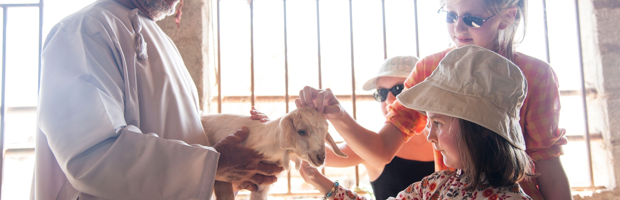 Oman mit Kindern - Oman Urlaub mit Kindern - Kinder streicheln eine Ziege