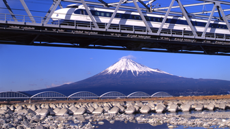 Ein Zug rauscht über eine Brücke vor dem Berg Fuji