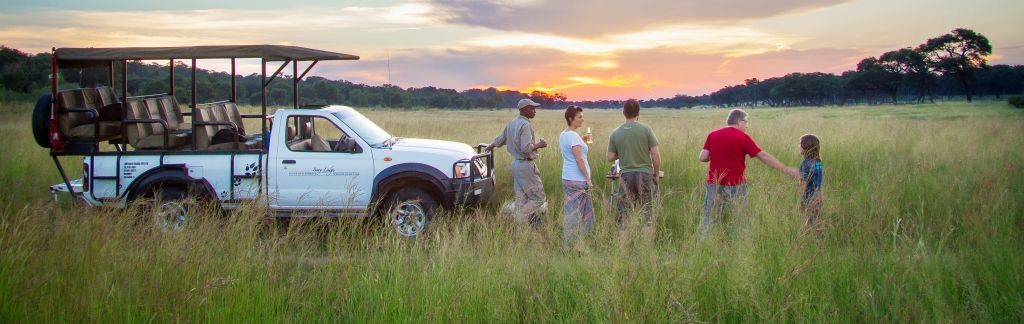 Botswana Familienreise - Botswana for family individuell - Jeep und Menschen vor Sonnenuntergang