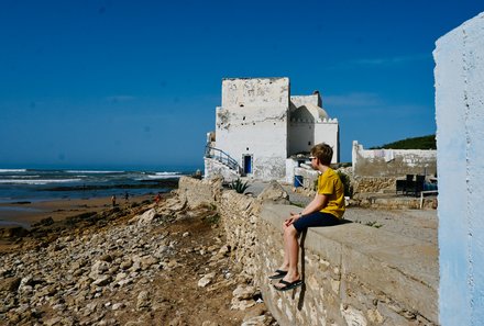 Marokko for family - Marokko Familienreise mit Kindern - Kind sitzt auf Mauer Essaouira