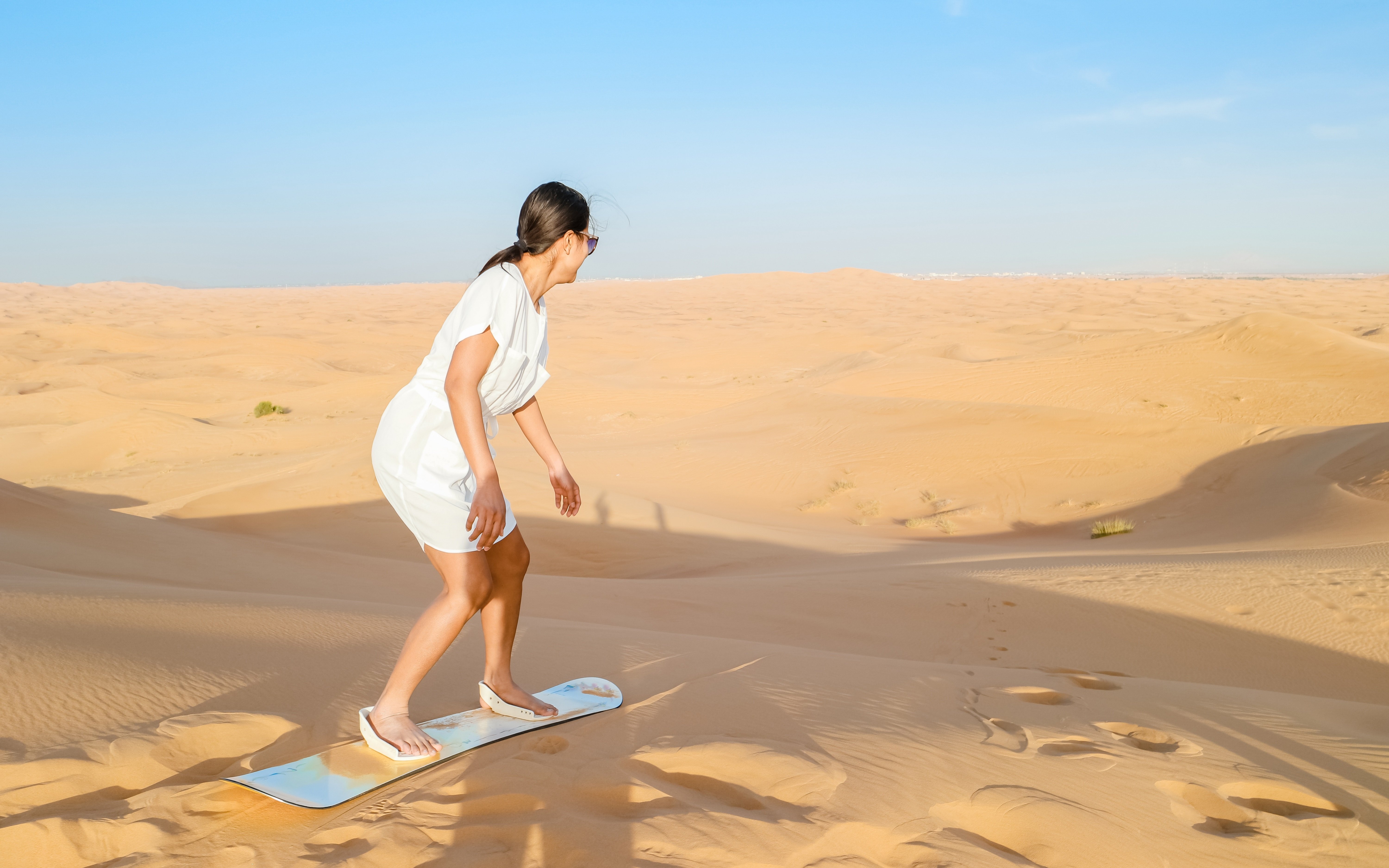 Oman mit Kindern - Oman Urlaub mit Kindern - Jugendliche beim Sandboarding in der Wüste