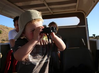 Kleinkind mit Fernglas auf Safari in Südafrika