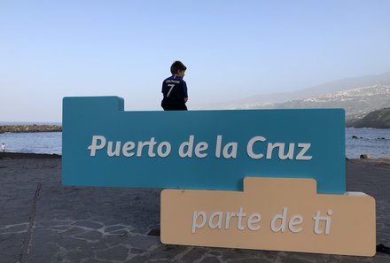 Teneriffa Familienurlaub - Teneriffa for family - Junge sitzt auf Puerto de la Cruz Schild