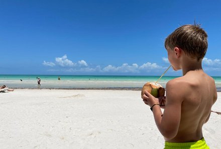 Mexiko mit Kindern - Mexiko Urlaub mit Kindern - Kind trinkt aus Kokosnuss am Strand