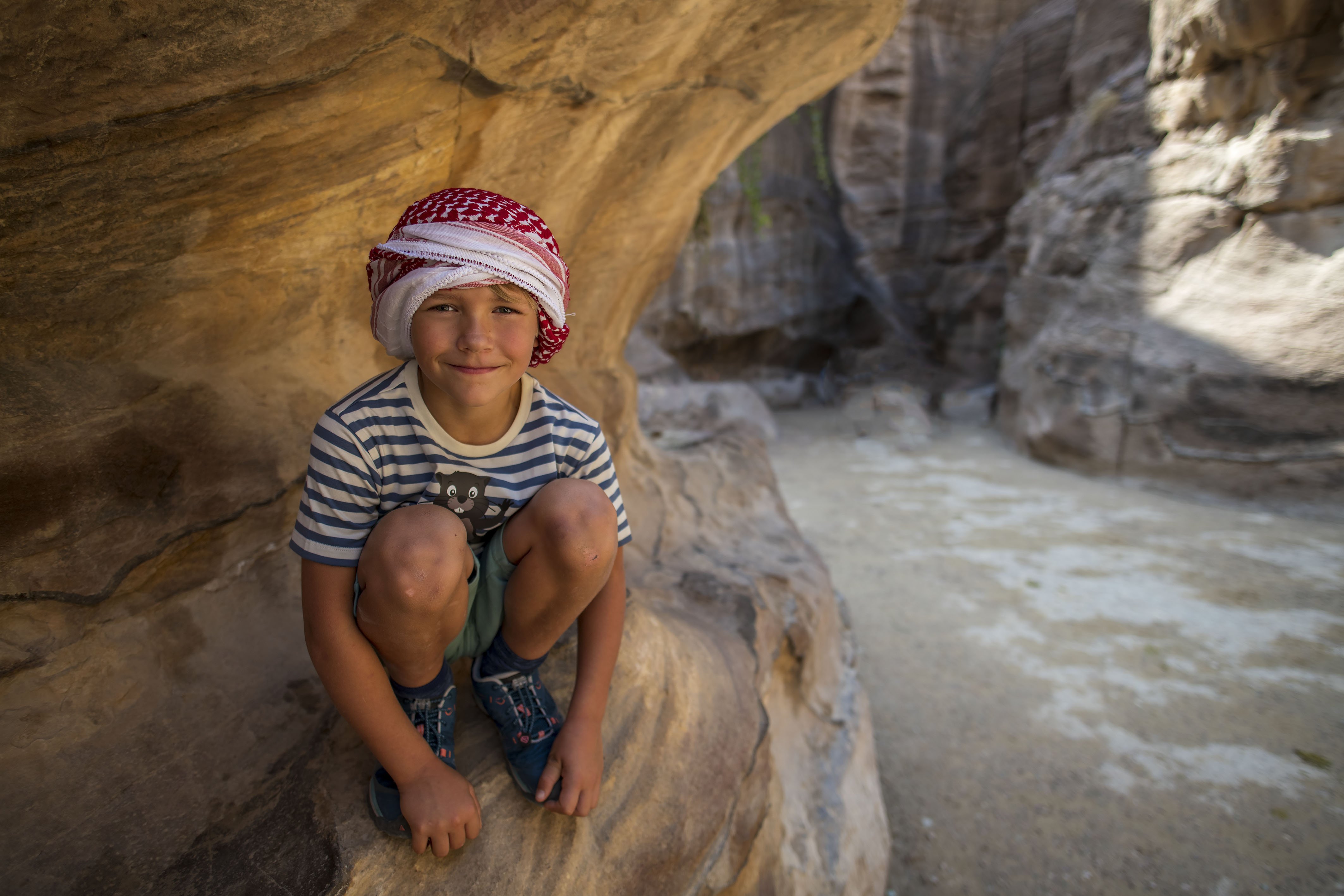 Jordanien mit Kindern - Jordanien Urlaub mit Kindern - Kind hockt in einem Felsen bei Petra