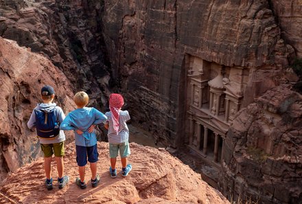 Jordanien Rundreise mit Kindern - Petra - drei Kinder stehen auf Felsen und blicken auf das Schatzhaus
