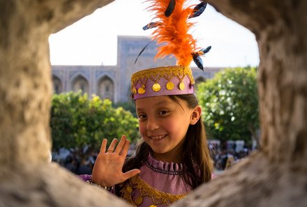 Usbekistan Familienreise - Mädchen hinter Loch winkt 