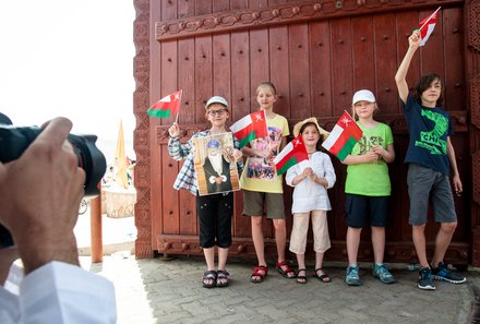 Oman mit Kindern - Oman Urlaub mit Kindern - Kinder wedeln mit der Flagge des Oman